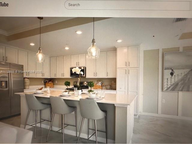 kitchen featuring white cabinets, hanging light fixtures, an island with sink, and appliances with stainless steel finishes