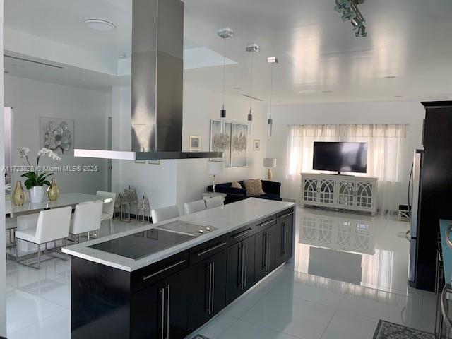 kitchen featuring a center island, pendant lighting, extractor fan, black electric stovetop, and light tile patterned floors