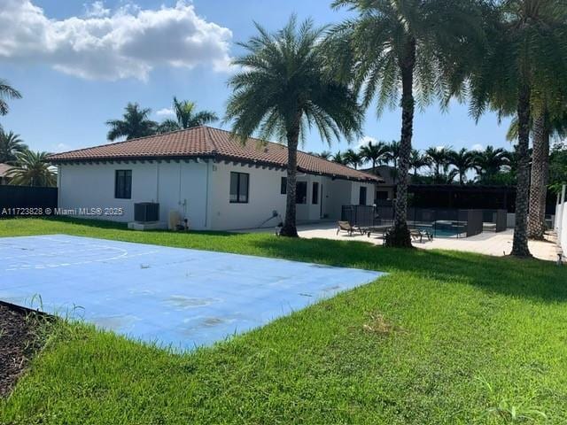 rear view of property with central AC, a yard, and basketball court