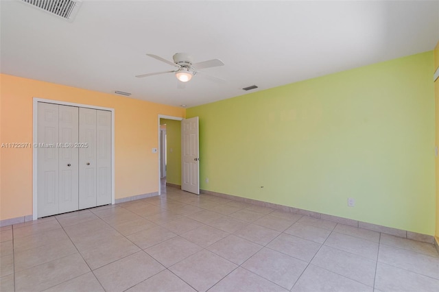 unfurnished bedroom featuring ceiling fan, light tile patterned flooring, and a closet