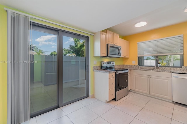 kitchen featuring light tile patterned floors, stainless steel appliances, a healthy amount of sunlight, and sink