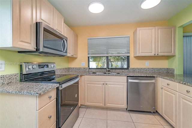 kitchen featuring light stone counters, sink, light tile patterned flooring, and appliances with stainless steel finishes