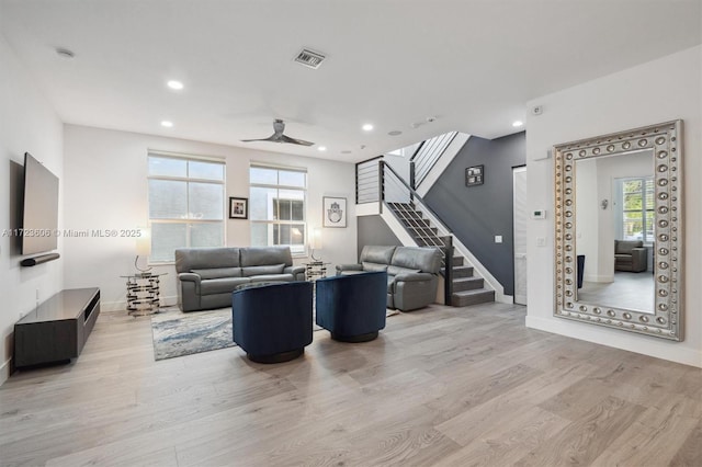 living room with light wood-style flooring, recessed lighting, visible vents, and stairway