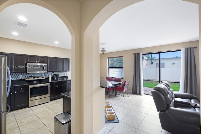 kitchen featuring stainless steel appliances, light tile patterned floors, and decorative backsplash