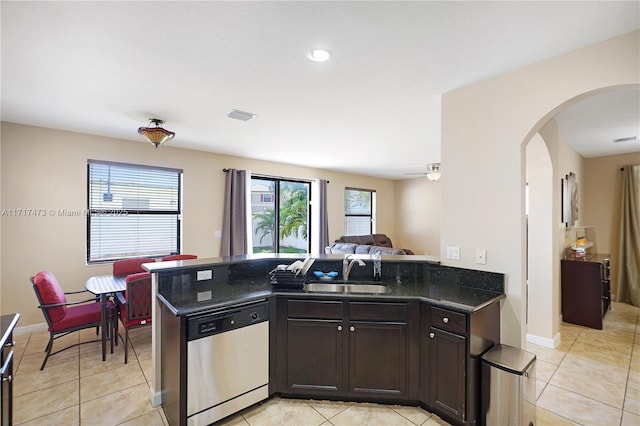 kitchen featuring sink, light tile patterned floors, dishwasher, dark stone countertops, and kitchen peninsula