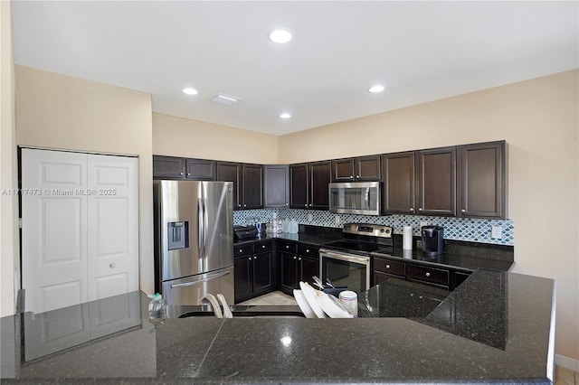 kitchen featuring tasteful backsplash, appliances with stainless steel finishes, dark brown cabinetry, and dark stone counters