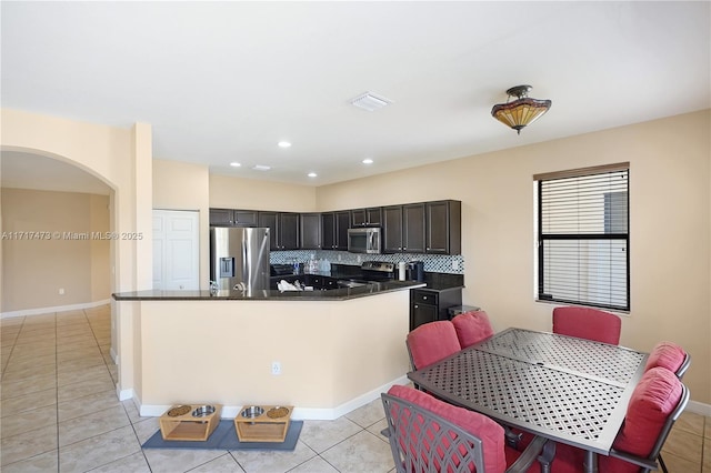 kitchen with light tile patterned floors, decorative backsplash, a center island, and appliances with stainless steel finishes