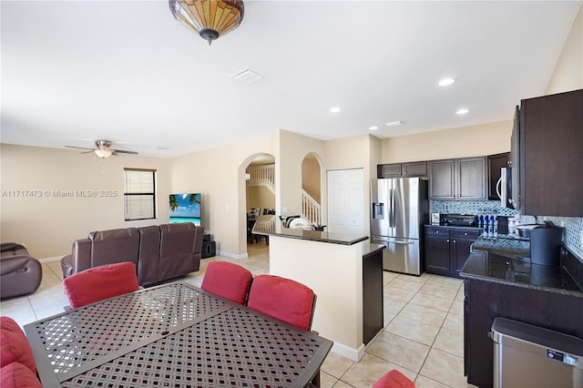 kitchen featuring ceiling fan, appliances with stainless steel finishes, tasteful backsplash, a kitchen island, and light tile patterned flooring