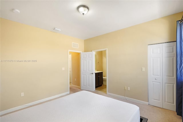 bedroom featuring light colored carpet, connected bathroom, and a closet