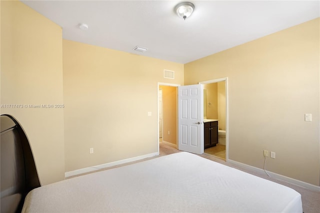 bedroom with ensuite bath and light colored carpet