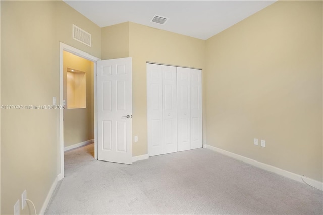 unfurnished bedroom with light colored carpet and a closet