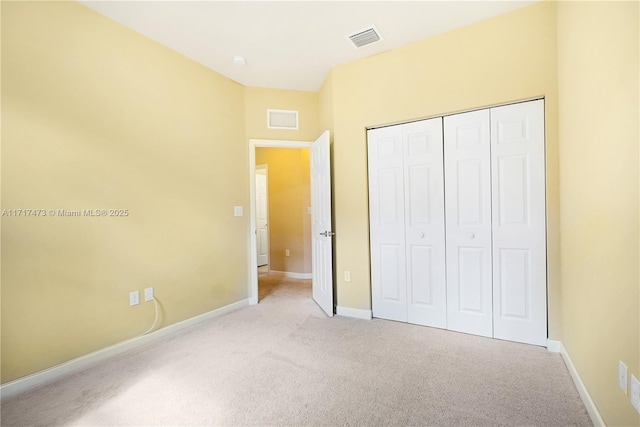 unfurnished bedroom featuring light colored carpet and a closet