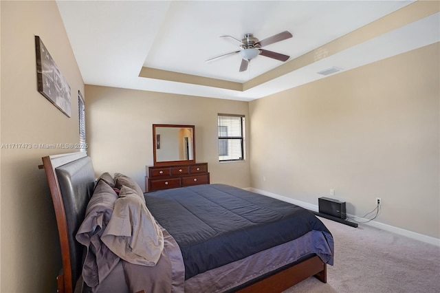 carpeted bedroom with ceiling fan and a raised ceiling