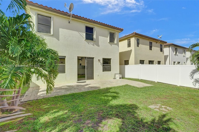 back of property with a patio area and a lawn