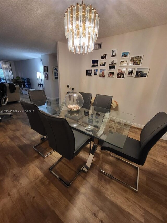 dining area featuring hardwood / wood-style floors, a textured ceiling, and an inviting chandelier