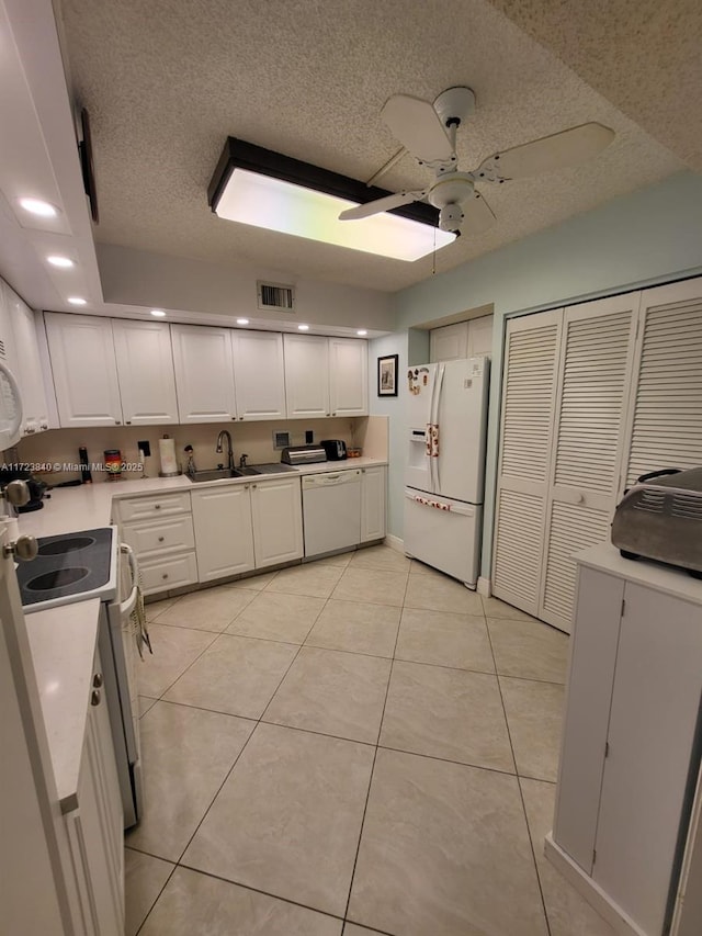 kitchen featuring white cabinetry, white appliances, light tile patterned flooring, and sink