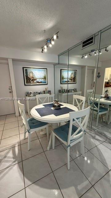 dining area with a textured ceiling and light tile patterned floors