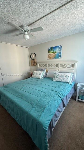 carpeted bedroom with a textured ceiling and ceiling fan