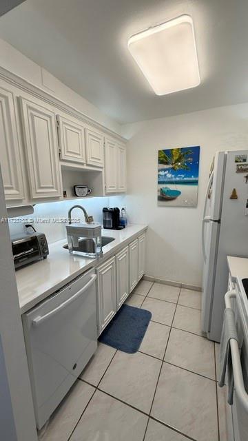 kitchen with stainless steel dishwasher, white fridge, light tile patterned floors, stove, and sink