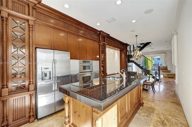 kitchen with sink, a kitchen breakfast bar, a notable chandelier, a center island with sink, and appliances with stainless steel finishes