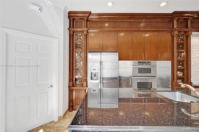 kitchen featuring stainless steel appliances, dark stone counters, and sink