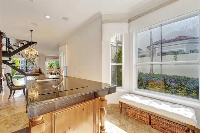 kitchen featuring sink, black electric cooktop, ornamental molding, light brown cabinetry, and a chandelier