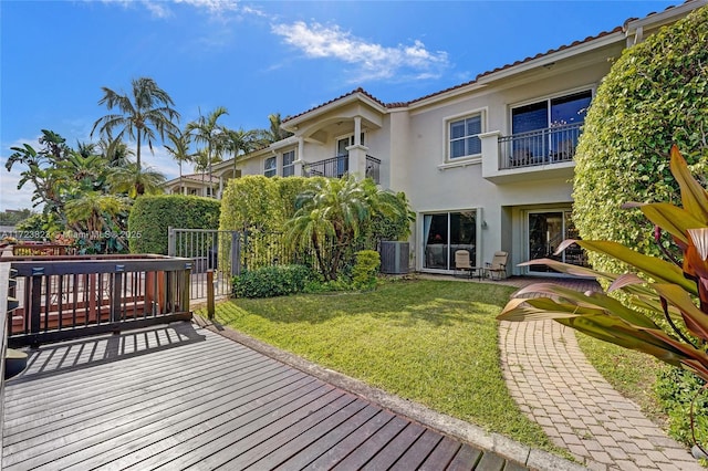 exterior space with central AC unit, a balcony, and a yard