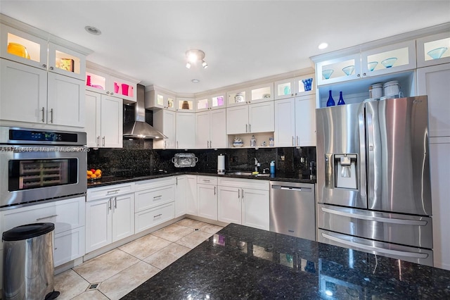 kitchen with wall chimney exhaust hood, decorative backsplash, white cabinets, and appliances with stainless steel finishes