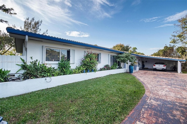 ranch-style home featuring a carport and a front lawn