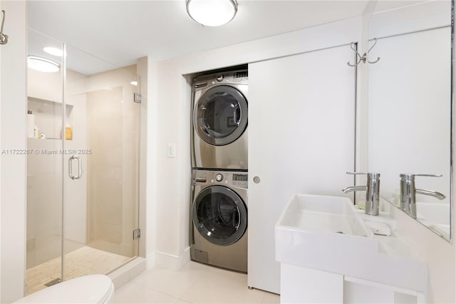 laundry room featuring light tile patterned floors, stacked washer / dryer, and sink