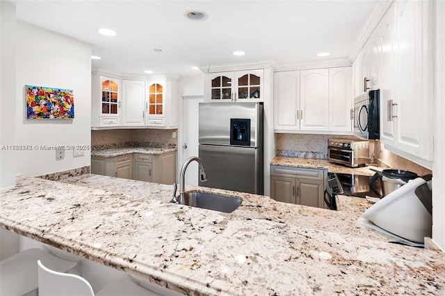 kitchen with kitchen peninsula, stainless steel appliances, white cabinetry, and sink