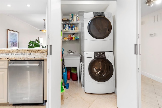 clothes washing area featuring stacked washing maching and dryer, ornamental molding, and light tile patterned floors