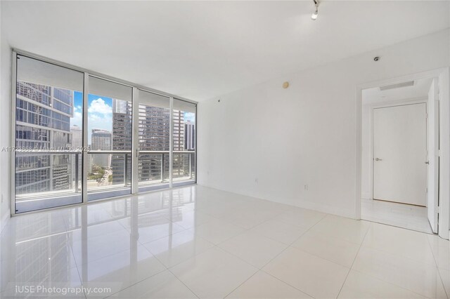 spare room with a wall of windows and light tile patterned flooring