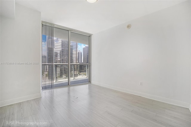 475 Brickell Ave Unit 2013, Miami, FL 33131 - unfurnished room featuring a view of city, baseboards, floor to ceiling windows, and wood finished floors