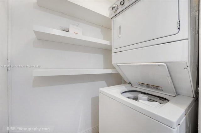 washroom featuring stacked washer and clothes dryer and laundry area