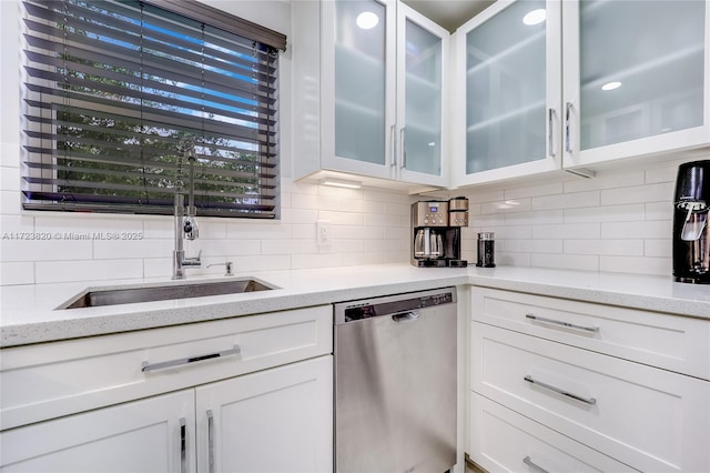 kitchen with stainless steel dishwasher, tasteful backsplash, white cabinetry, and a sink