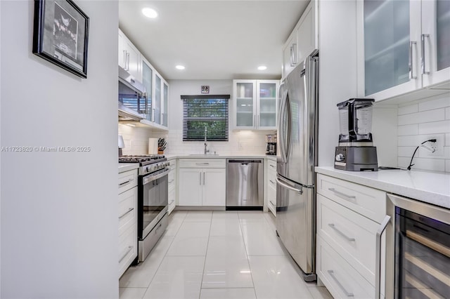 kitchen featuring sink, appliances with stainless steel finishes, white cabinets, light tile patterned flooring, and beverage cooler