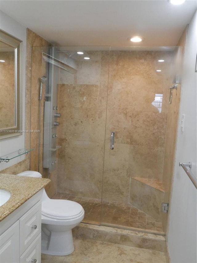 bathroom with toilet, vanity, and a shower with door