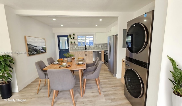 dining area with stacked washer and clothes dryer, sink, and light hardwood / wood-style floors