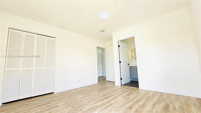 unfurnished bedroom with a closet and light wood-type flooring