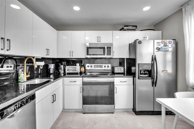 kitchen with sink, white cabinets, light tile patterned floors, backsplash, and appliances with stainless steel finishes