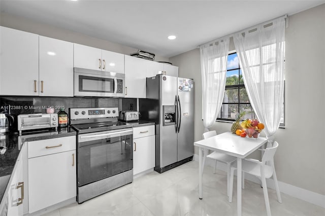 kitchen with dark stone counters, appliances with stainless steel finishes, tasteful backsplash, and white cabinetry