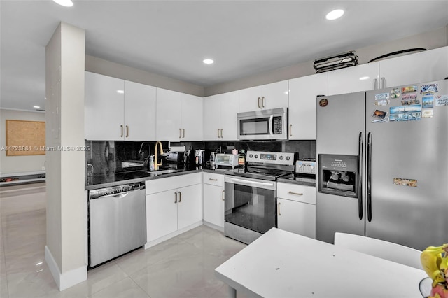 kitchen with appliances with stainless steel finishes, white cabinets, sink, and tasteful backsplash