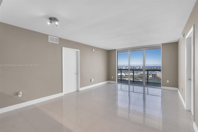 empty room with expansive windows and light tile patterned flooring