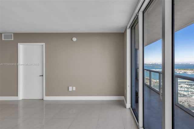 spare room featuring expansive windows, a water view, and light tile patterned floors