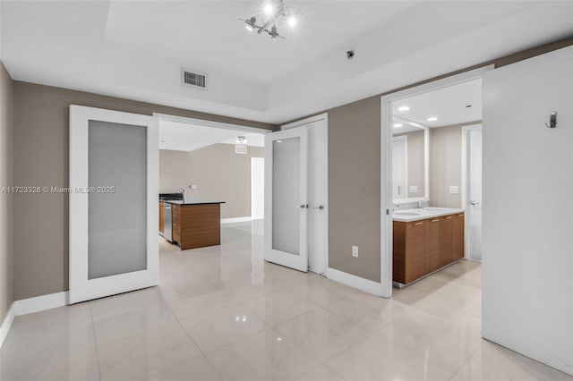 interior space featuring french doors, connected bathroom, light tile patterned floors, and sink