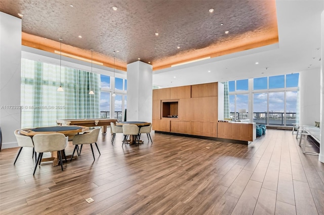 interior space with light hardwood / wood-style floors, floor to ceiling windows, and a tray ceiling