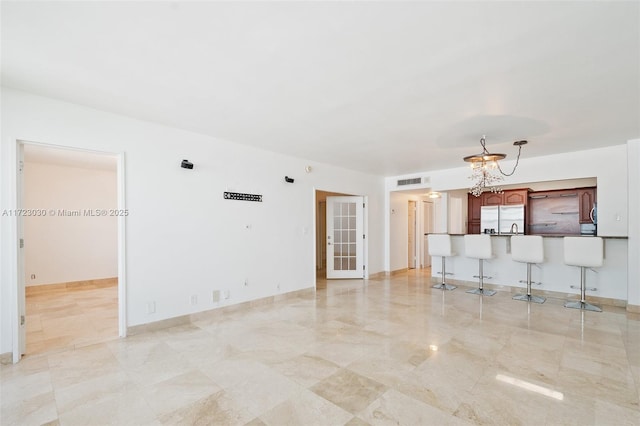 unfurnished living room featuring a notable chandelier