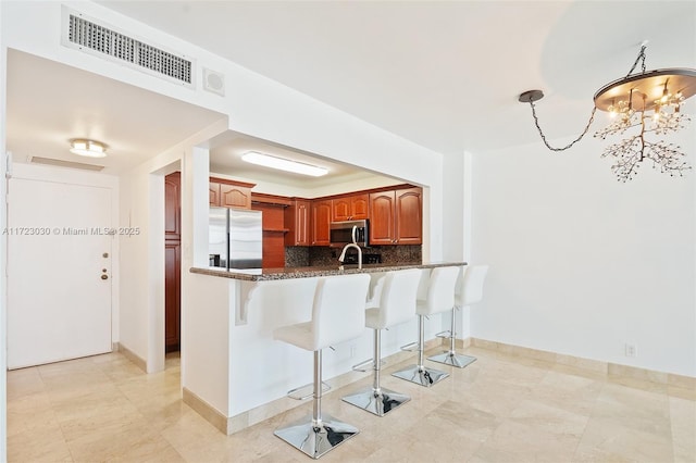 kitchen with pendant lighting, a breakfast bar, stainless steel appliances, tasteful backsplash, and kitchen peninsula