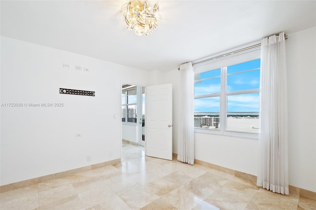 unfurnished room featuring a chandelier